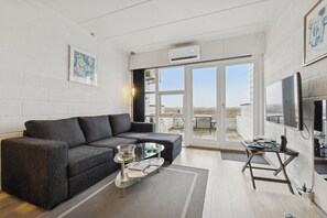 Ein modernes Wohnzimmer mit einem Ecksofa, einem Glastisch und einem großen Fernseher.