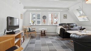 Ett vardagsrum med en tv, en soffa, ett soffbord och en mönstrad matta.