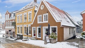 En traditionell europeisk byggnad med ett sluttande tak, stora fönster och en gata som är belagd med tegelstenar.