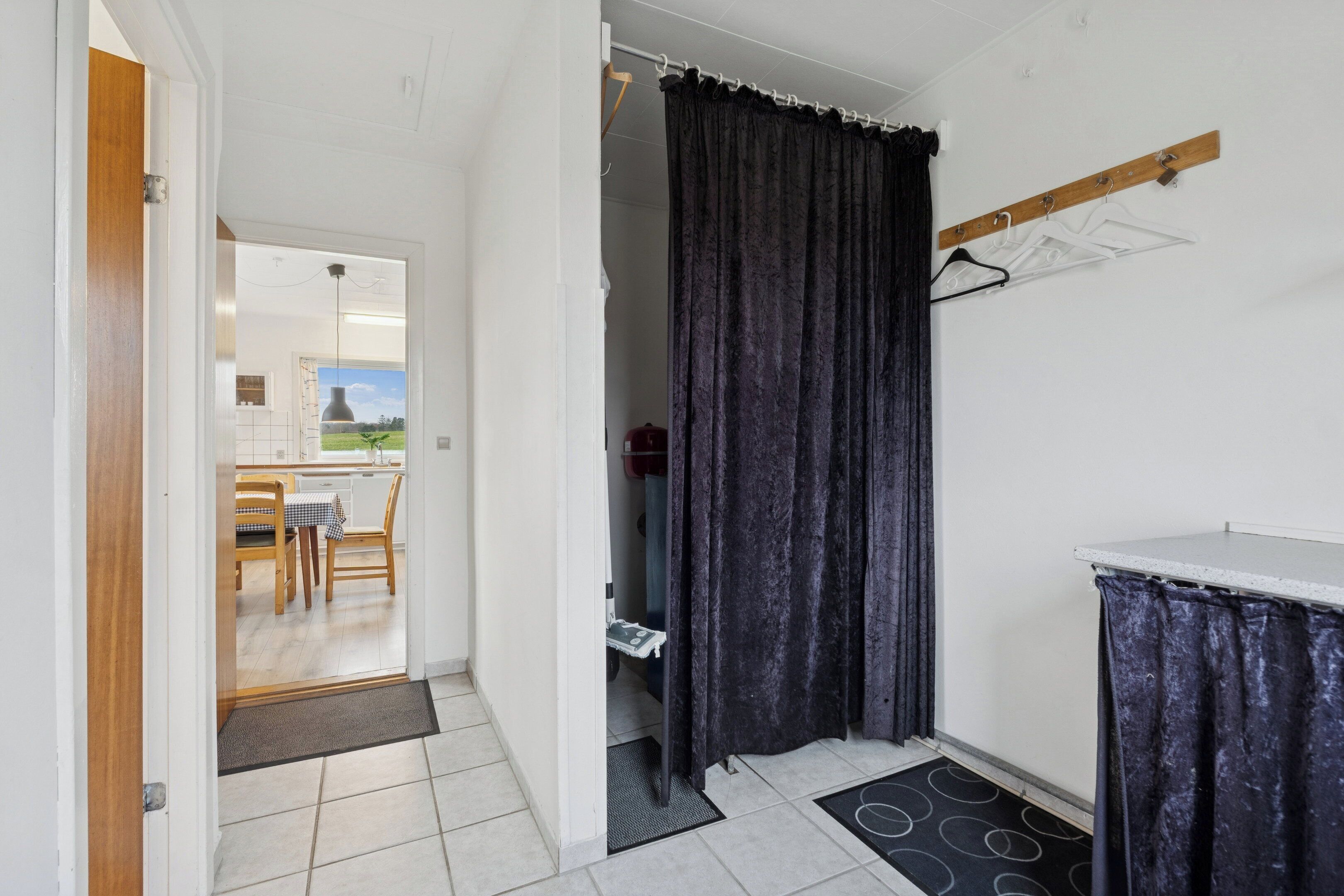 Une pièce avec une porte donnant sur un coin repas, un rideau de douche et un porte-manteau.