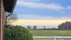 A view of a grassy field with a wooden fence and a brick building in the foreground. - Holiday home on large grounds with beautiful view (Humble)