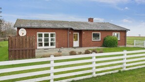 A brick house with a white fence, a satellite dish, and a small garden. - Holiday home on large grounds with beautiful view (Humble)