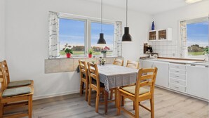 A modern kitchen with a dining table, chairs, pendant lights, and a view of the outdoors. - Holiday home on large grounds with beautiful view (Humble)