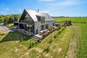 Ein modernes, zweistöckiges Haus mit Satteldach, großen Fenstern und einem Balkon.