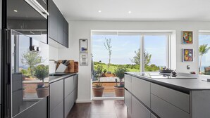 Una cocina moderna con vistas al exterior, ventanas amplias y plantas en macetas.