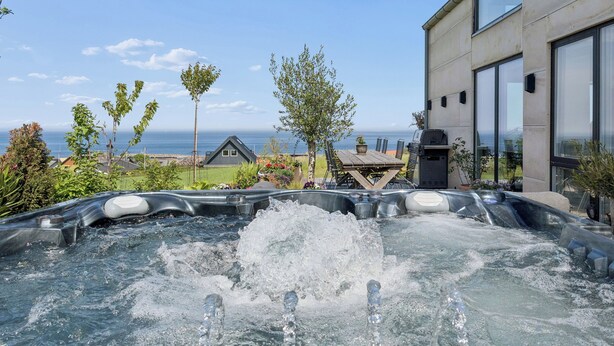 Un jacuzzi con chorros de agua, una terraza de madera y vista al océano.