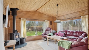 A cozy cabin interior with a wooden interior, a sofa, a table, and a fireplace. - Cozy holiday home near the water (Dannemare)