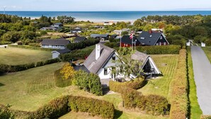 A coastal residential area with houses, a flag, and a view of the sea. - Idyllic summer house with sea view (Glesborg)