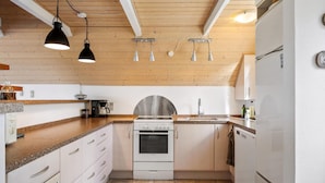 A modern kitchen with a stainless steel stove, white cabinets, and a wooden ceiling. - Idyllic summer house with sea view (Glesborg)