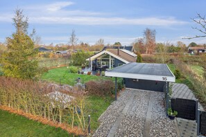 A residential property with a covered patio, a well-maintained lawn, and a small shed. - Beautiful summer house from 2008 outdoor spa (Nakskov)