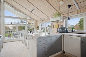 Una cocina con una isla grande, armarios blancos y vistas al exterior.