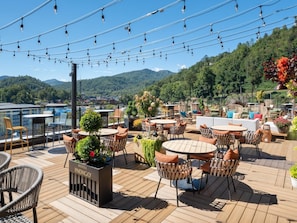 A rooftop terrace with outdoor seating, a view of the mountains, and a sign for Hotel Indigo. - New Build • Hot Tub • Firepit (Sevierville)
