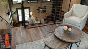 Eine hohe Wohnung mit Balkon, einem runden Holztisch mit einer Schale und einem weißen Sessel.