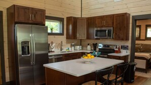 Eine moderne Küche mit Holzausbau, Edelstahlgeräten und einer zentralen Kochinsel mit Barhocker.
