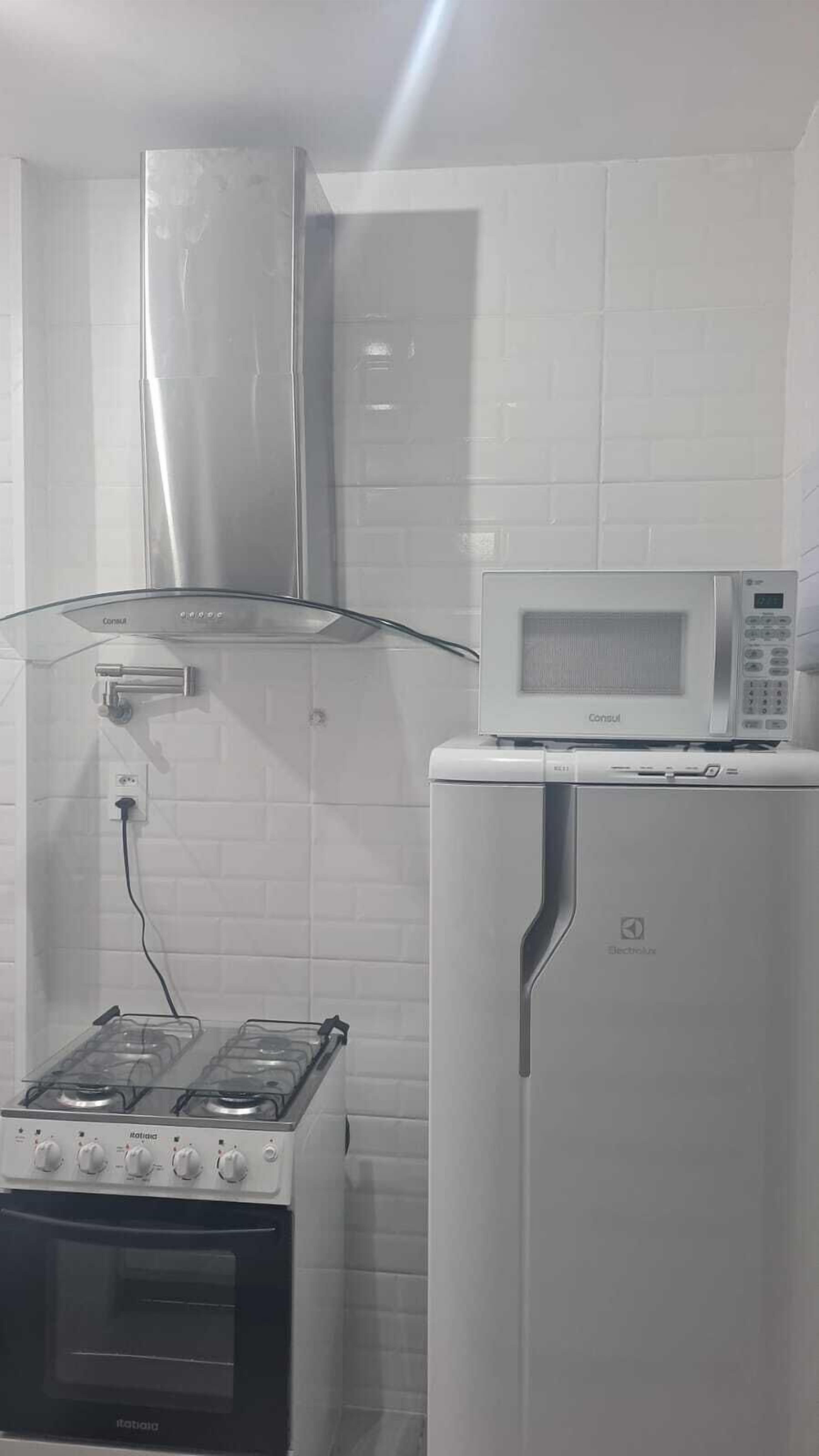 A kitchen with a gas stove, a microwave, and a refrigerator.