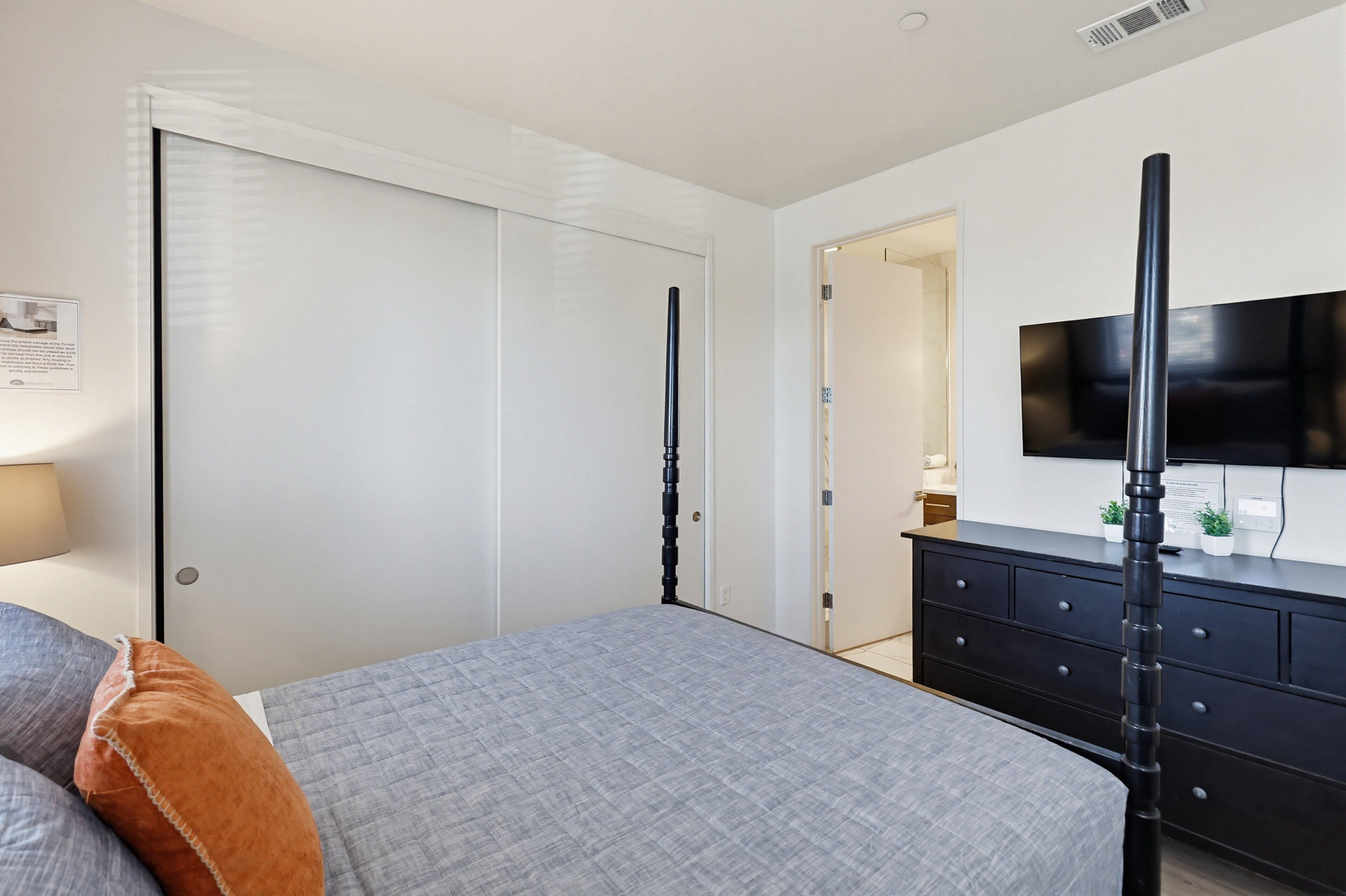 Ein Schlafzimmer mit Bett, Kommode, Fernseher und Kleiderschrank.