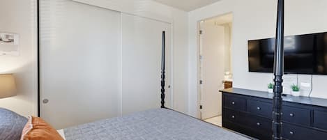 Un dormitorio con cama, cómoda, televisión y armario.