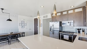A modern kitchen with a large island, stainless steel appliances, and pendant lighting. - Ocean Park Combo 9 & 10 (San Diego)