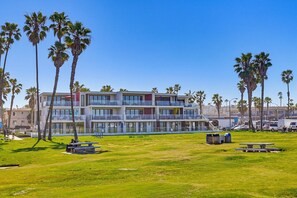 A multi-story hotel with balconies, a grassy lawn, and palm trees. - Ocean Park Combo 9 & 10 (San Diego)