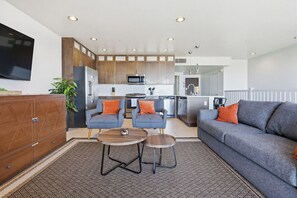 A modern kitchen with built-in appliances, a dining area with two chairs and a table, and a living room with a sofa and a coffee table. - Ocean Park Combo 9 & 10 (San Diego)