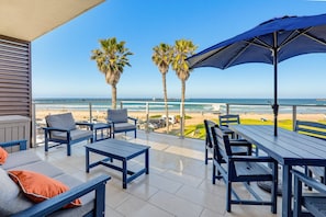 A terrace with outdoor seating, palm trees, and a view of the beach. - Ocean Park Combo 9 & 10 (San Diego)