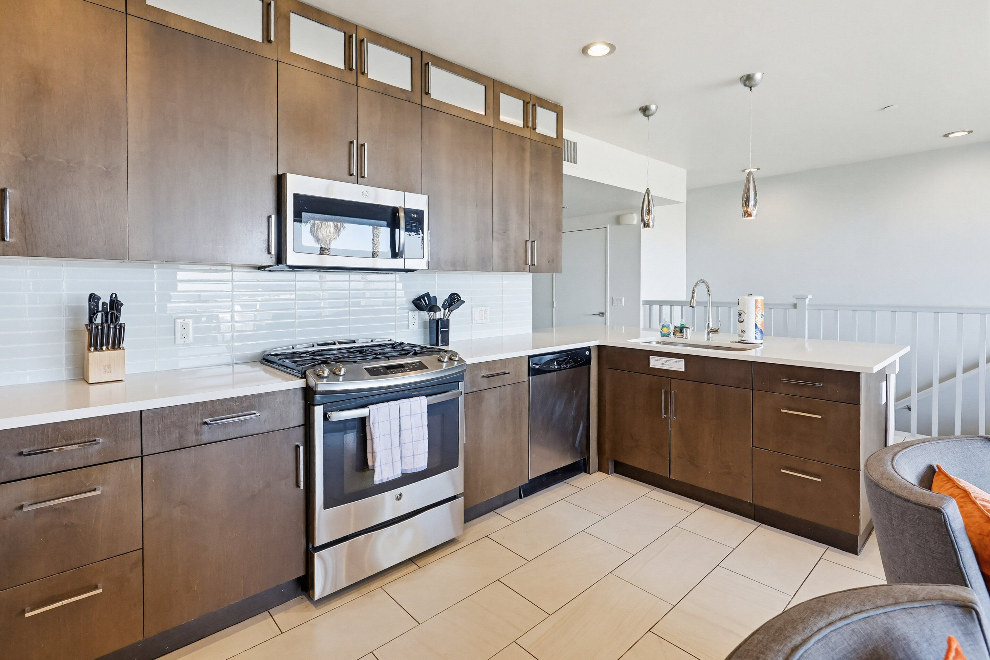 A modern kitchen with stainless steel appliances, wooden cabinets, and a white countertop.