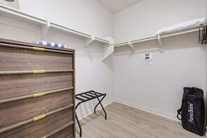 A room with a wooden dresser, a metal drying rack, a black bag, and white storage shelves. - Ocean Park Combo 9 & 10 (San Diego)