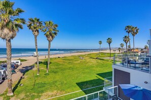 A beach view with palm trees, a clear sky, and a modern building with a balcony. - Ocean Park Combo 9 & 10 (San Diego)