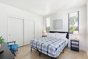 A bedroom with a bed, a desk, a chair, and a window with blinds. - Ocean Park Combo 9 & 10 (San Diego)