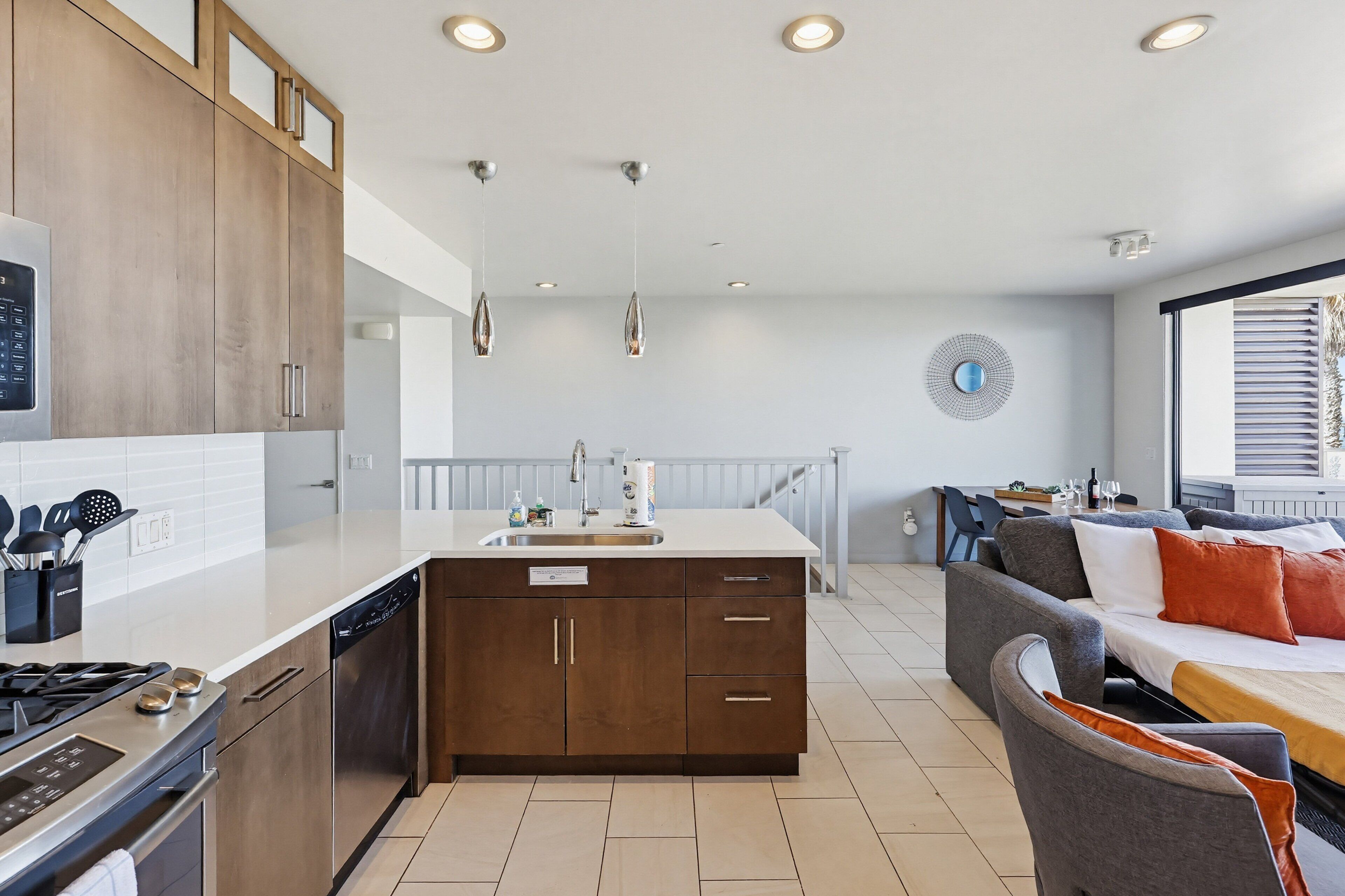 A modern kitchen with a dishwasher, stove, and a dining area with a sofa and table.