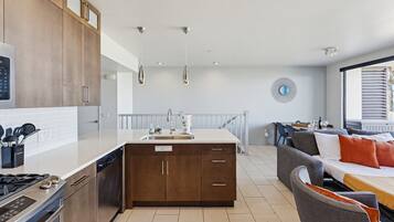 A modern kitchen with a dishwasher, stove, and a dining area with a sofa and table.