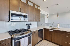 A modern kitchen with stainless steel appliances, wooden cabinets, and a white countertop. - Ocean Park Combo 9 & 10 (San Diego)