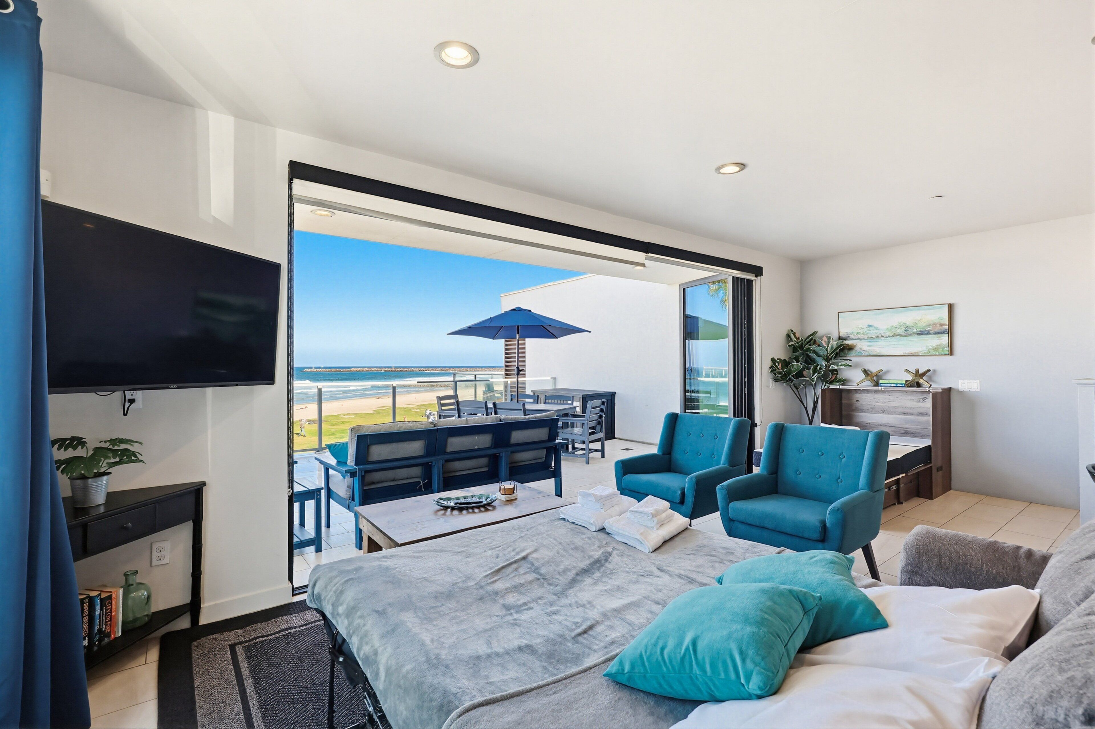 Une chambre moderne dotée d’un lit, d’une télévision, d’un balcon avec mobilier d’extérieur et offrant une vue sur l’océan.