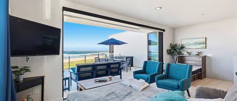 Une chambre moderne dotée d’un lit, d’une télévision, d’un balcon avec mobilier d’extérieur et offrant une vue sur l’océan.