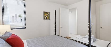 Une chambre à coucher avec un lit, un ventilateur de plafond, une fenêtre avec des stores et une porte.