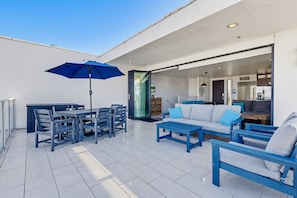 An outdoor patio with a dining table, chairs, a blue umbrella, and a sofa set. - Ocean Park Combo 9 & 10 (San Diego)