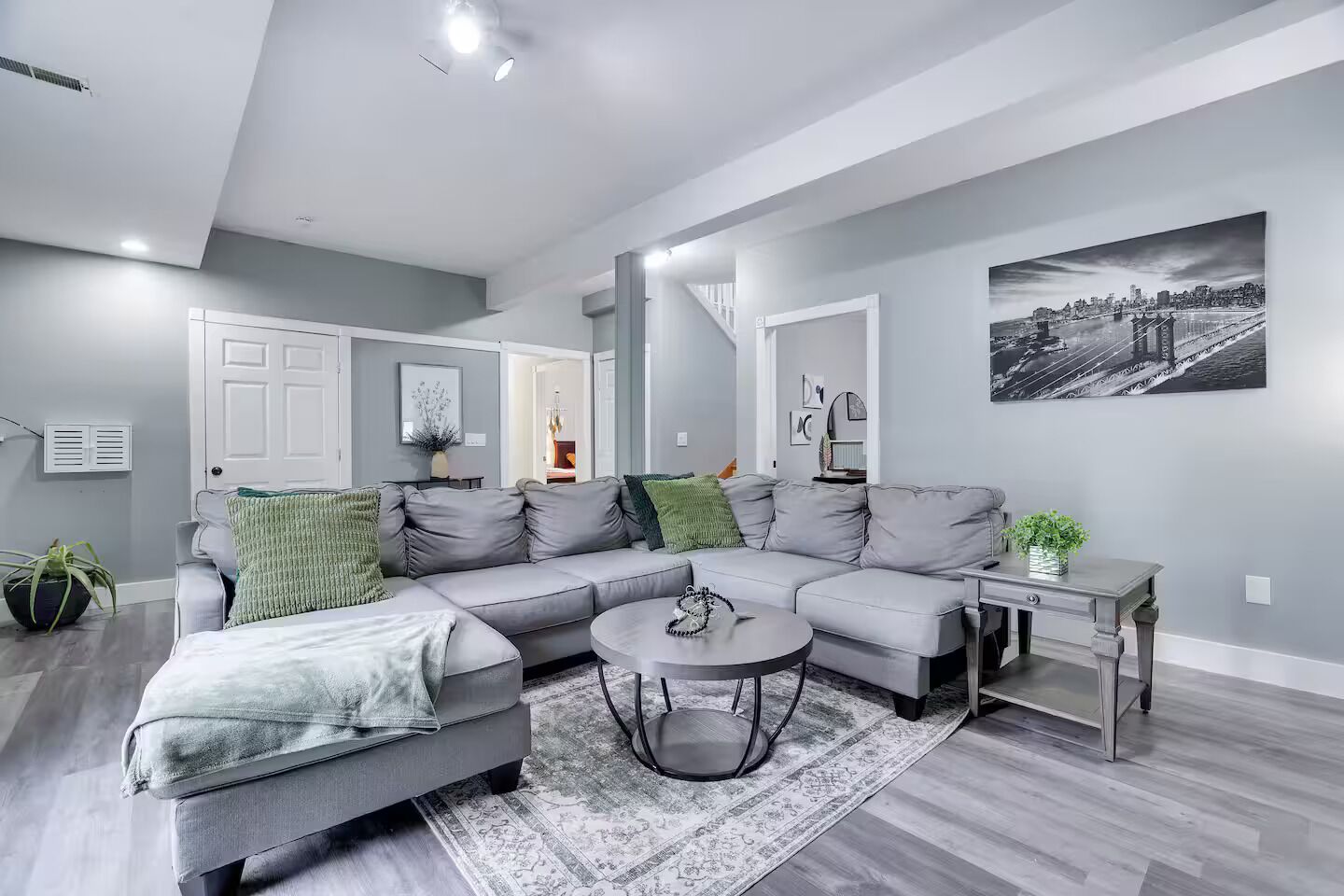 A modern living room with a grey sectional sofa, a round coffee table, and a dining table.