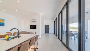 A modern kitchen with a large island, a flat-screen TV, and a dining area with chairs. - La Paz Dream Home: Ocean Views, Family Fun & BBQ Evenings (La Paz)