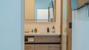 A modern bathroom with a white vanity, a large mirror, and a wooden cabinet below. - La Paz Dream Home: Ocean Views, Family Fun & BBQ Evenings (La Paz)