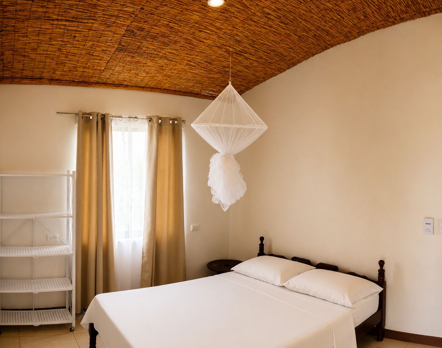 A bedroom with a bed, a shelf unit, a mosquito net, and a ceiling with a woven pattern.
