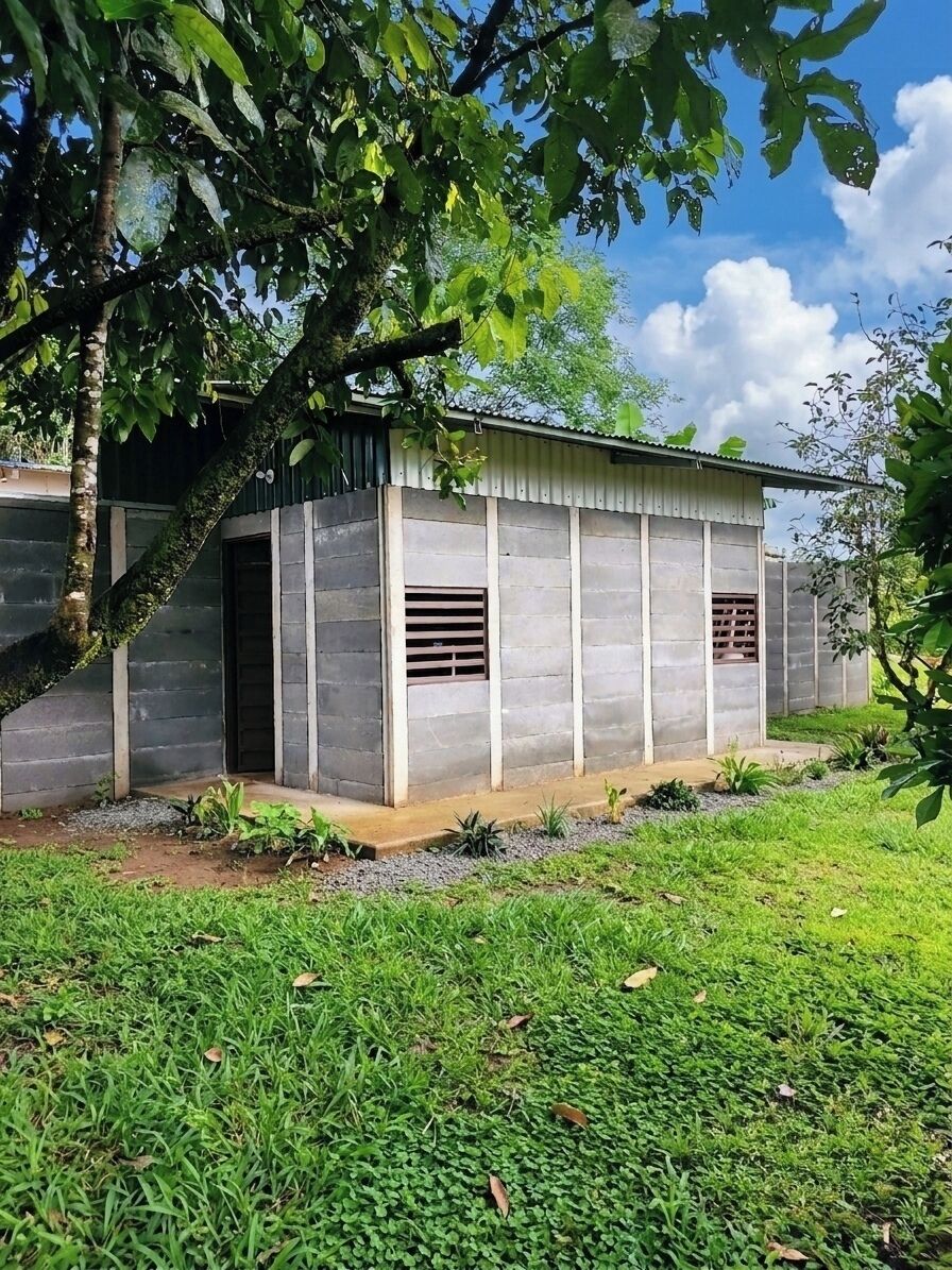 Un bâtiment à l’extérieur en béton, doté d’une porte et de fenêtres avec des barreaux horizontaux.