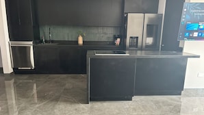 Una cocina moderna con armarios oscuros, horno empotrado y cafetera.