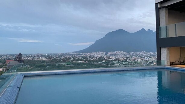 Una piscina en la azotea con vistas a una montaña y al paisaje urbano.