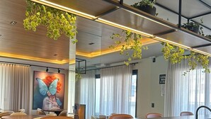 Eine moderne Küche mit Einbauofen, Edelstahlspüle und Arbeitsplatte. Über der Arbeitsplatte hängen Pflanzen und ein großes Fenster mit Vorhängen.