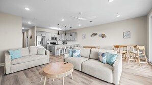En moderne stue med sofa, rundt sofabord og spiseplads med træbord og stole.