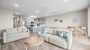 Ein modernes Wohnzimmer mit einer Couch, einem runden Couchtisch und einem Essbereich mit einem Holztisch und Stühlen.