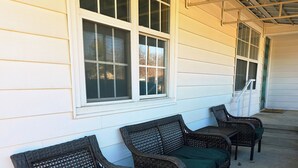 A covered porch with wicker furniture and a concrete floor.