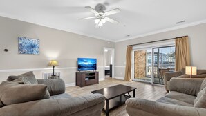 A living room with a sofa set, a coffee table, a TV, and a ceiling fan. - Relax by the Pool Near Beach & Golf Courses | Magnolia Pointe Luster Leaf 4833-105 (Myrtle Beach)