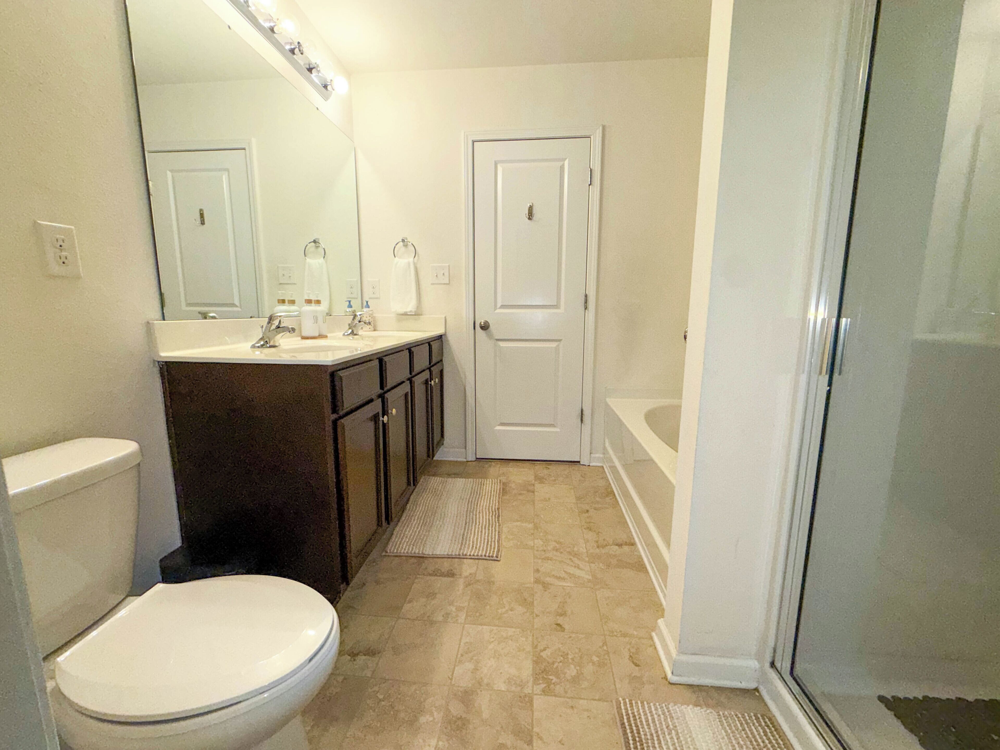 A bathroom with a toilet, sink, mirror, and shower.