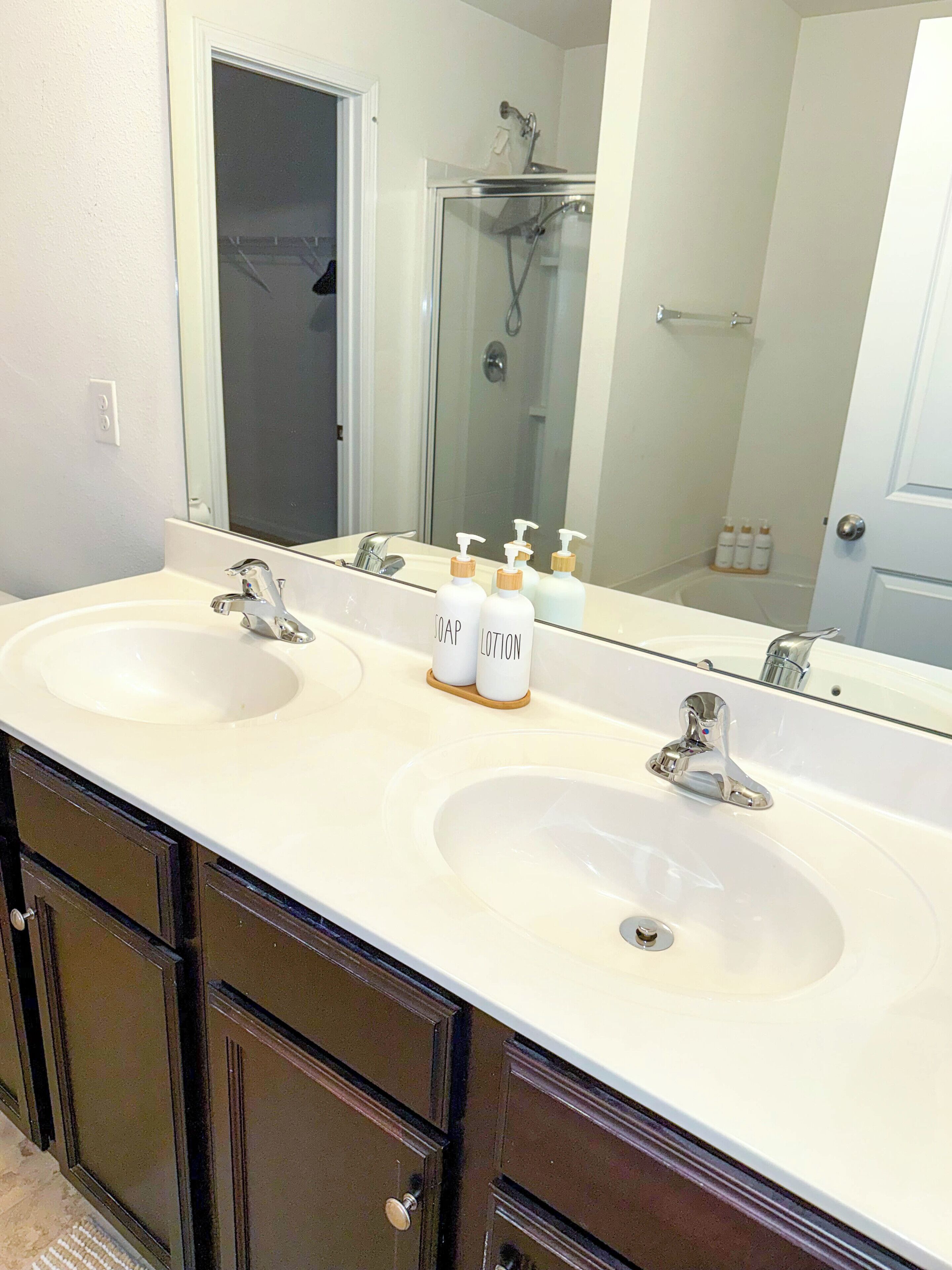 Une salle de bain avec deux lavabos, une douche et un miroir.